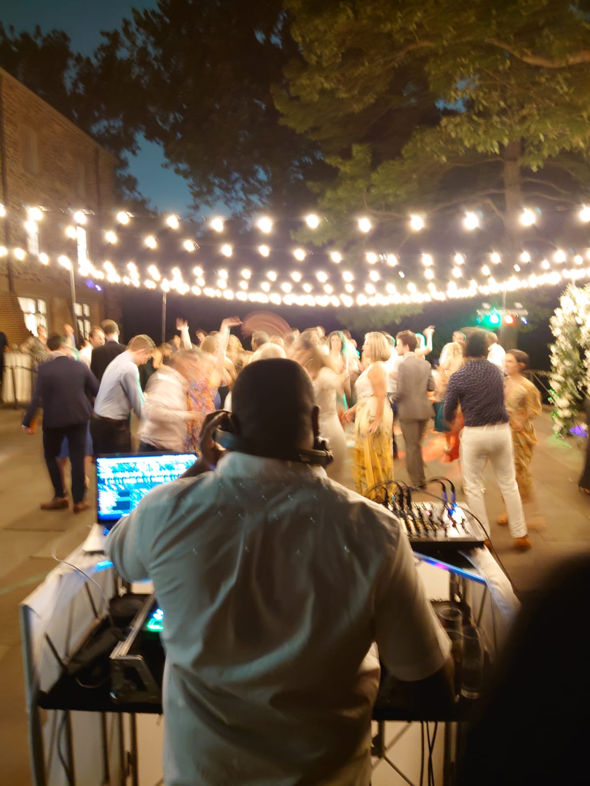 View from the DJ booth over a packed outdoor wedding dance floor