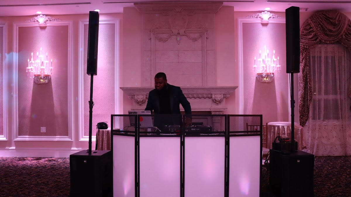 Wedding DJ setup illuminated with warm pink uplighting
